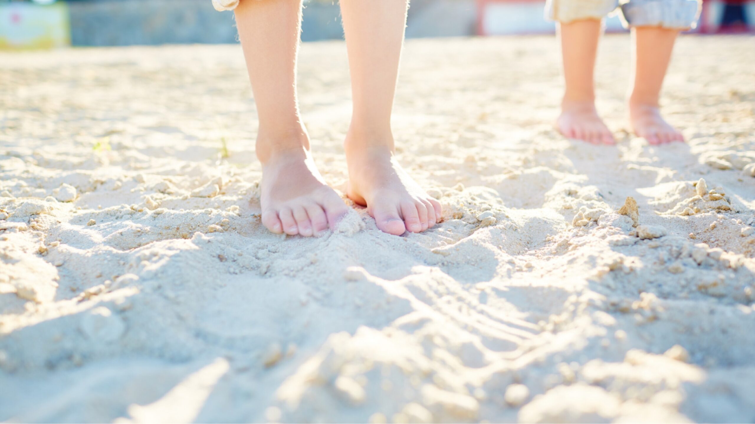 Kinder, die im Sand Barfuß laufen