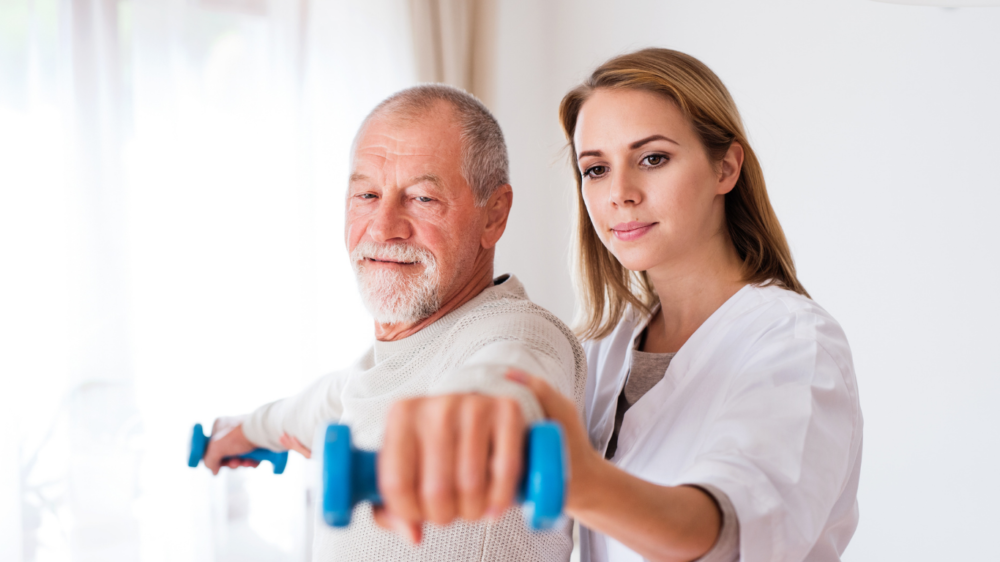 Physiotherapeut macht Übung mit Patient daheim