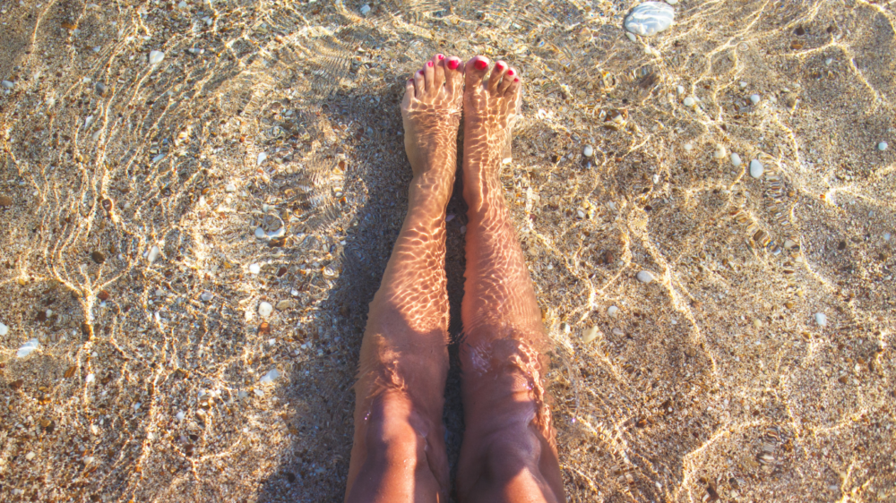 Damenbeine am Strand am Meer