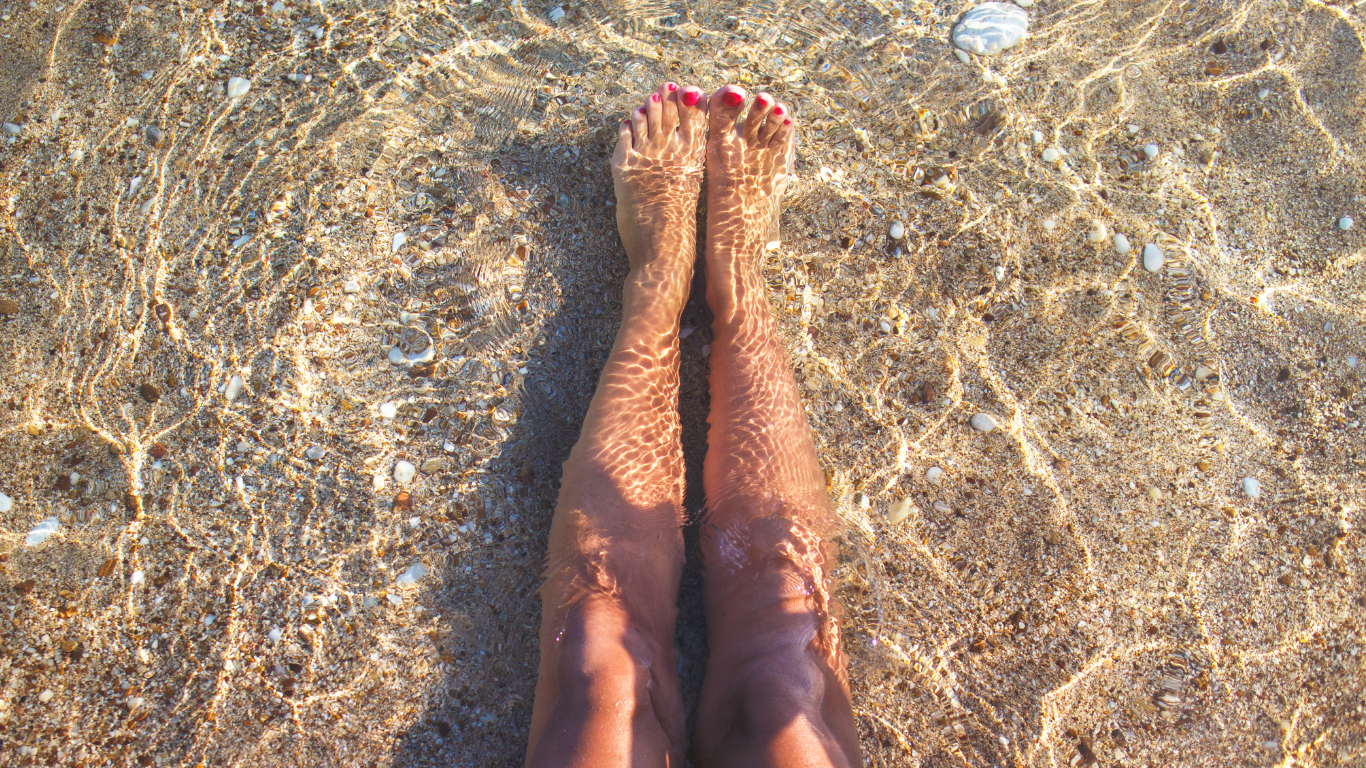 Damenbeine am Strand am Meer