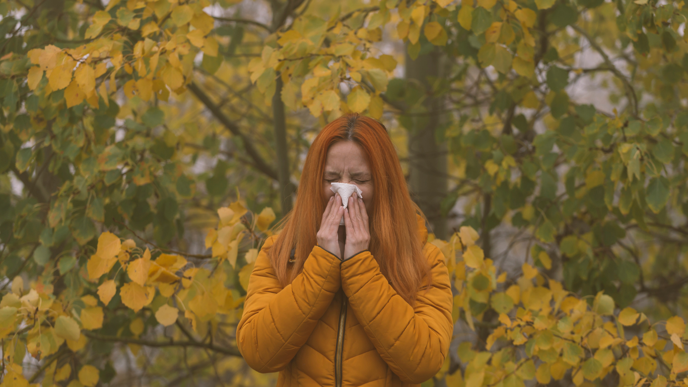 Frau, die drausen in der Natur steht und Schnupfen hat